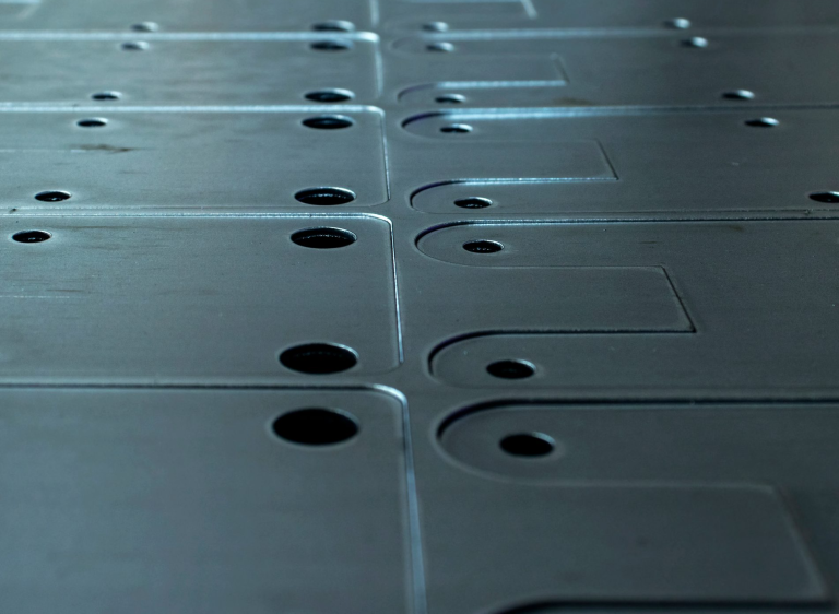 Stacked laser-cut metal components with rounded corners and drilled holes