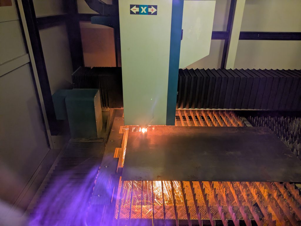 Laser cutting mild steel from inside the machine with visible sparks and heat during cut.
