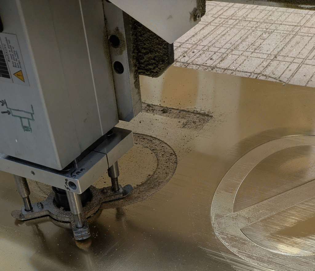 CNC engraving detailed lettering into brass sheet metal at MS Laser Services.