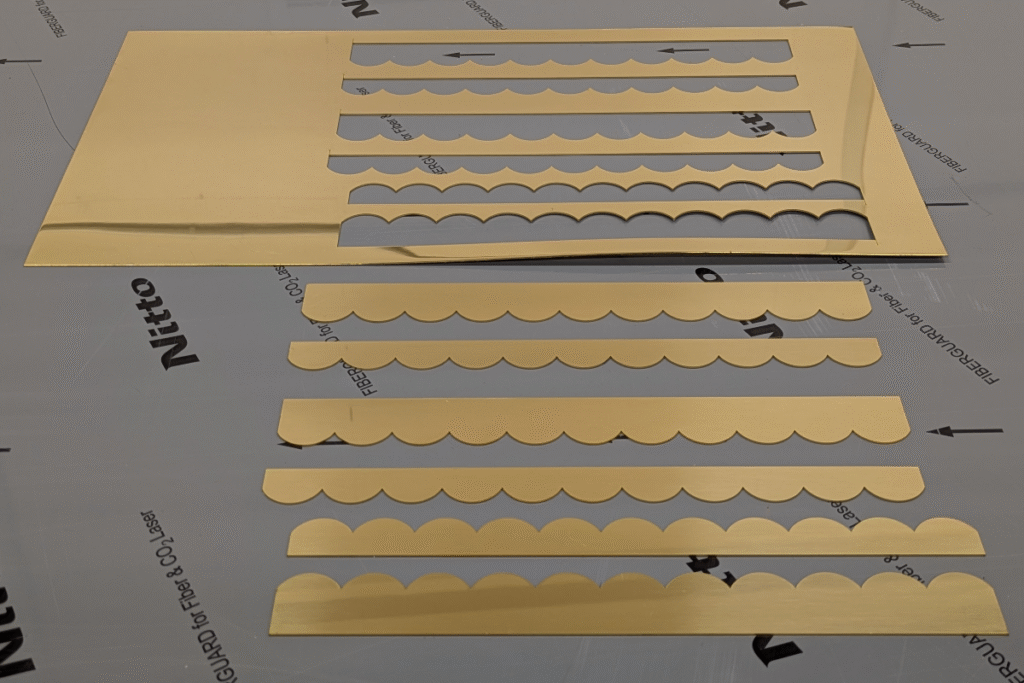 Production run of laser-cut brass components arranged on table